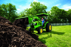 Compact tractor with multiple attachments performing home maintenance tasks like mowing, grading, and material handling