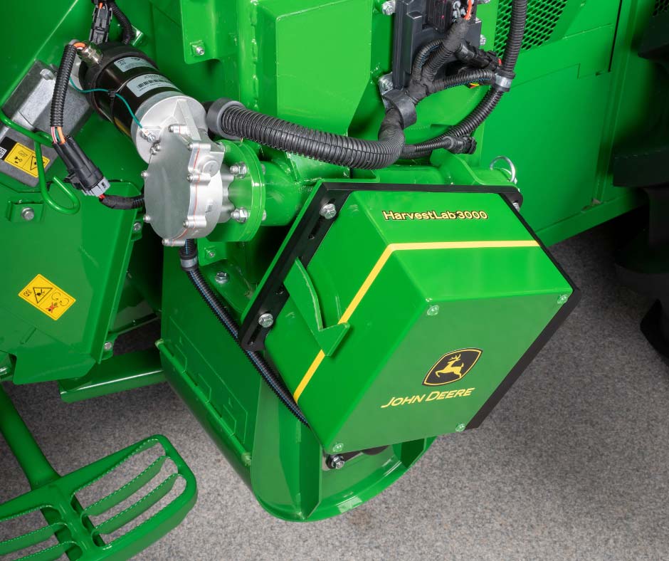 Green John Deere wood chipper with motor and hoses visible, showing internal mechanical components and yellow safety label.