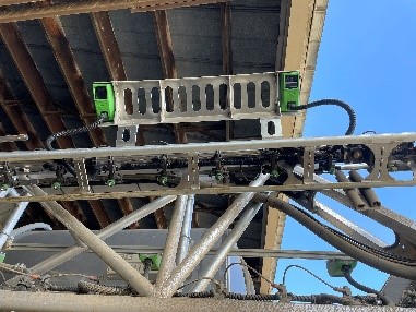 Industrial crane or hoist equipment mounted on steel structural framework against blue sky.